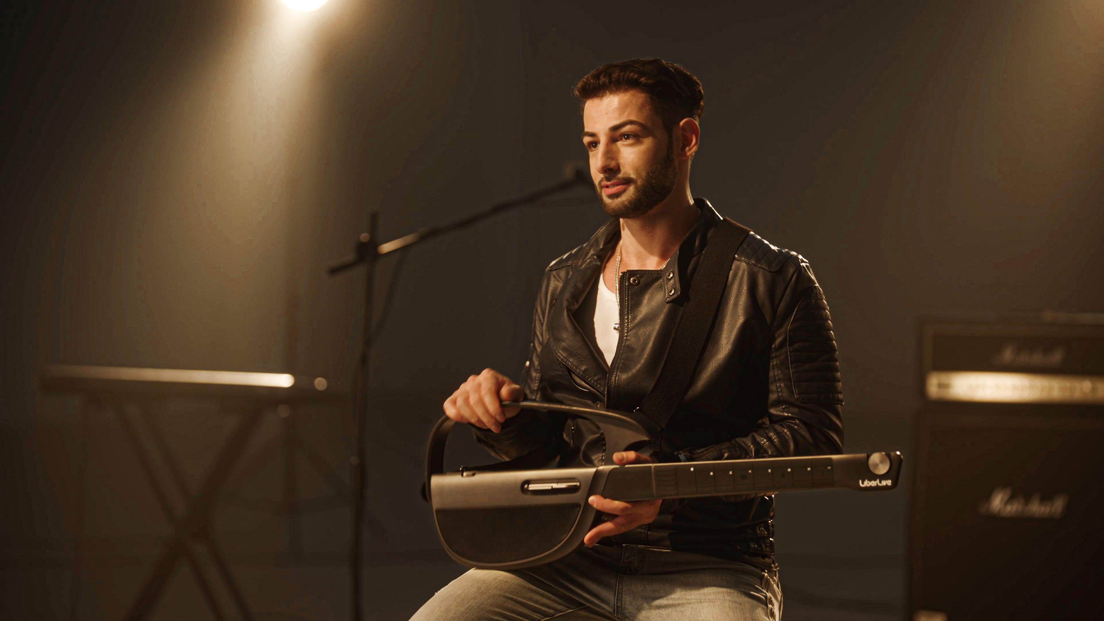 Musician holding a black LiberLive C1 stringless smart guitar in a stage-style performance setting