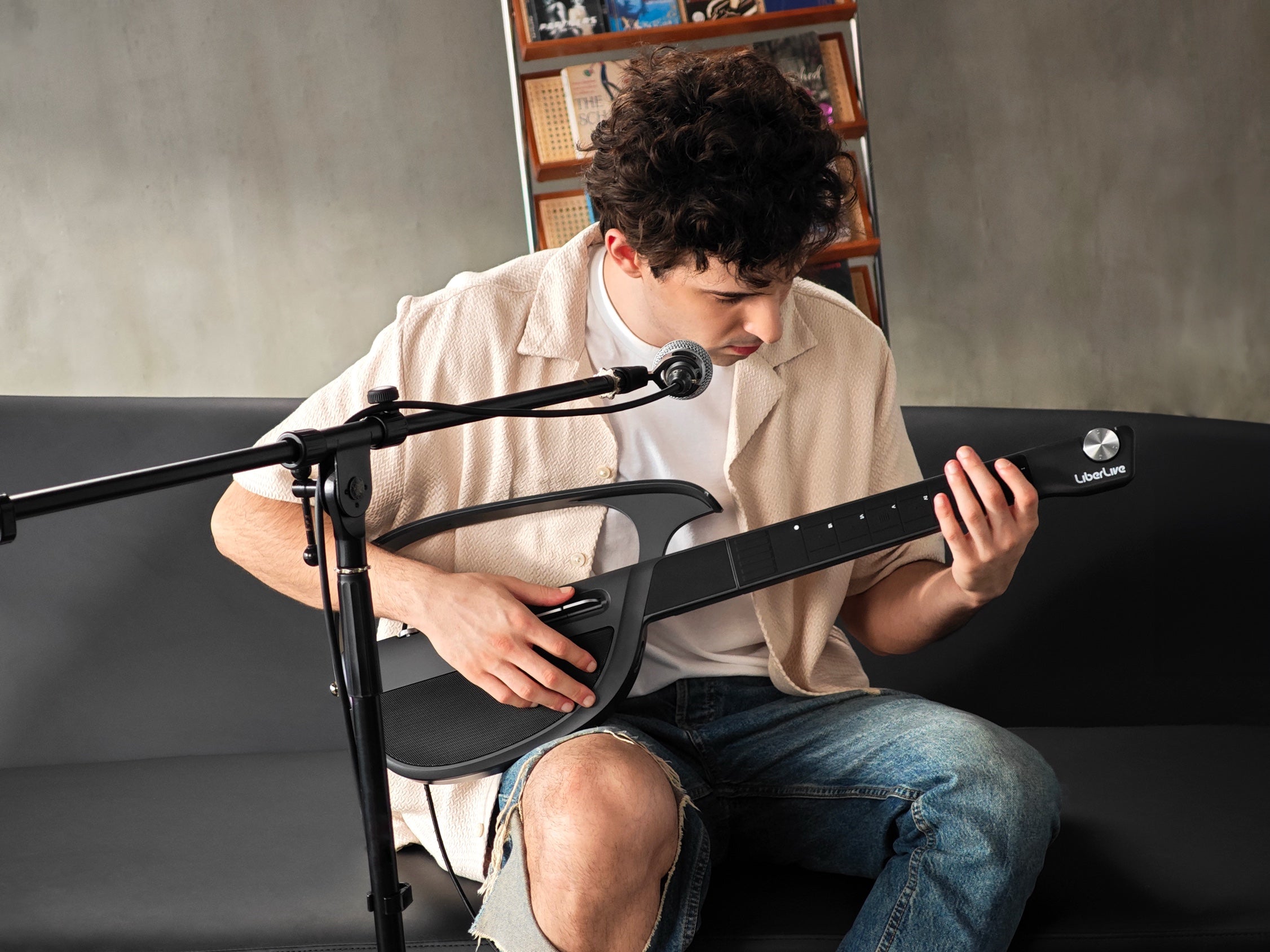 Musician playing a black LiberLive C1 while following app-guided chords in a studio setup