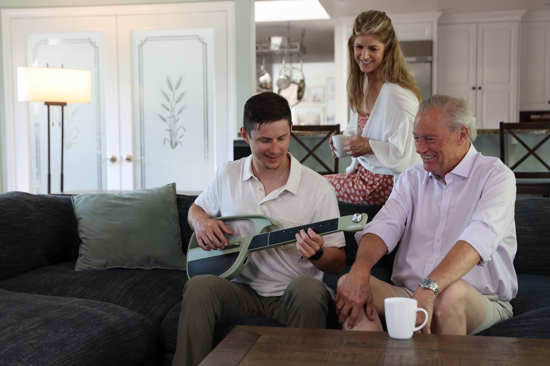 Beginner playing a LiberLive C1 smart guitar at home while family members listen