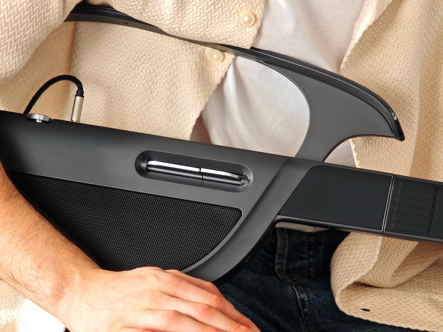 Close-up of the LiberLive C1 strumming paddle and body controls on a black stringless smart guitar