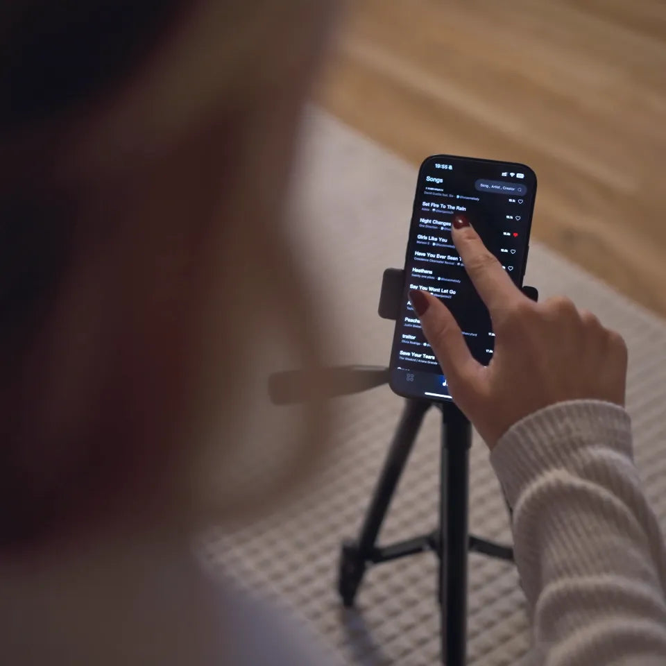 A phone on a stand showing the LiberLive app song library.